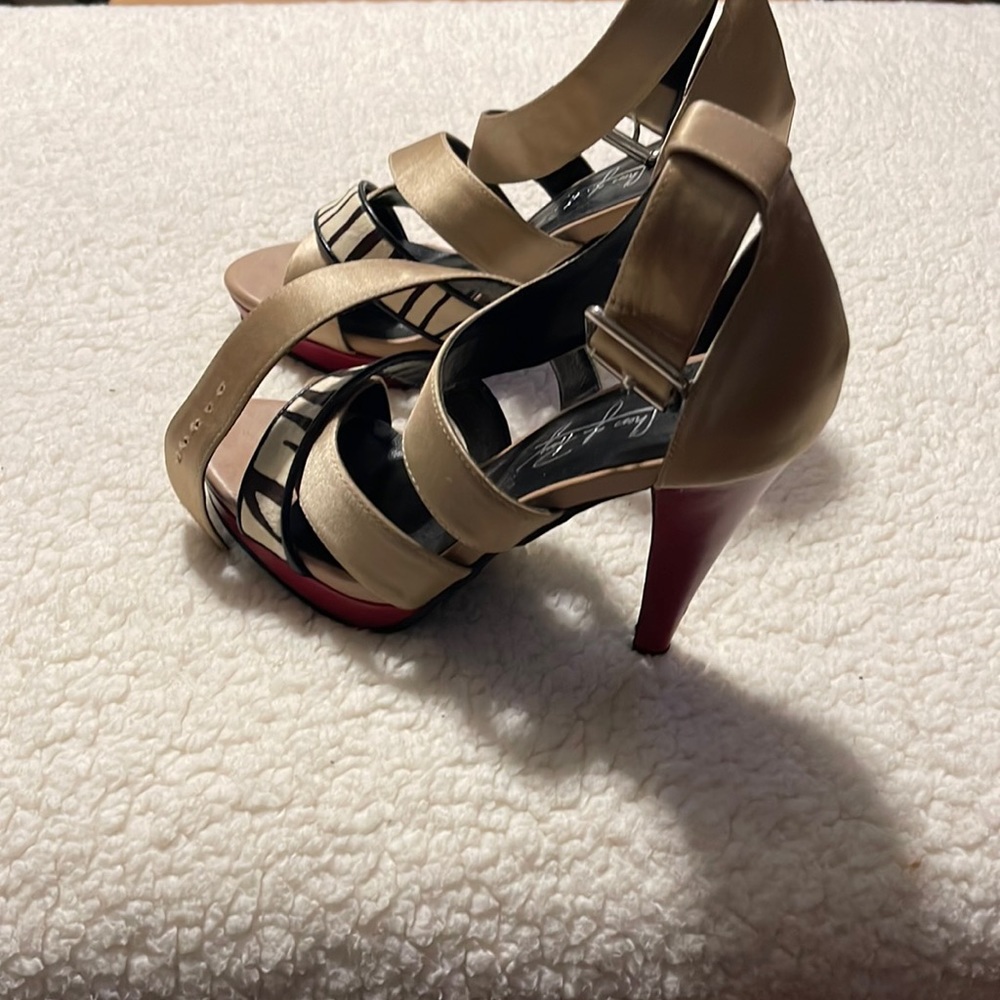 Taupe color sandal with zebra print on one of the bottom straps with a red heel